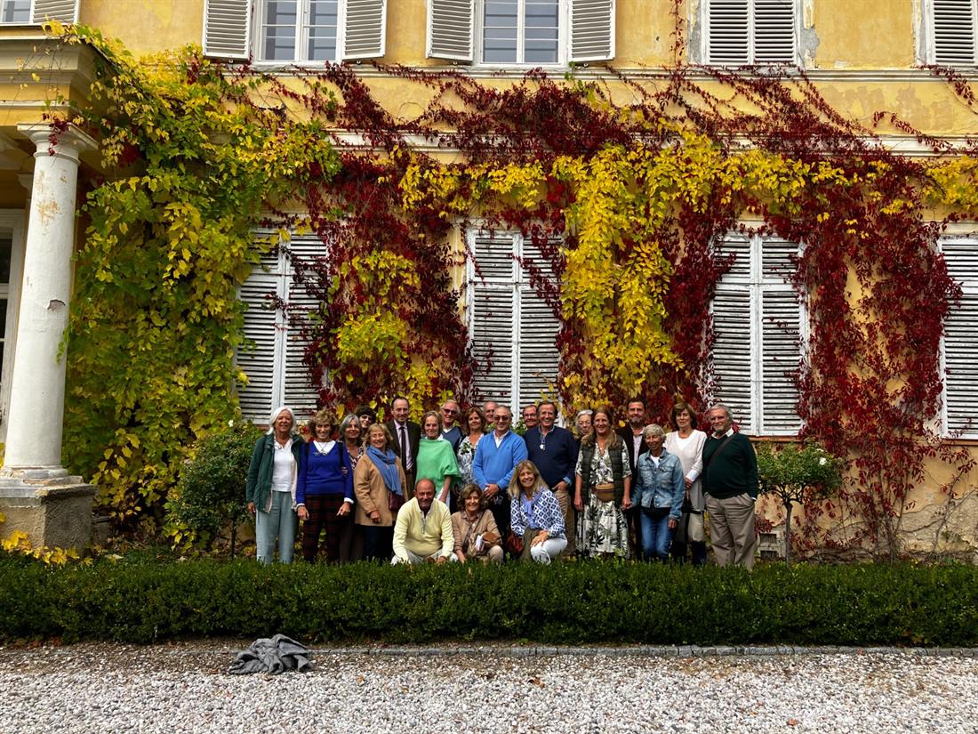 Grupo de viajantes da Quinto Império em frente a um palácio coberto de vinha virgem em tons de outono
